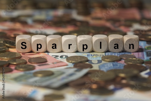 sparplan - Holzwürfel mit Buchstaben im Hintergrund mit Geld, Geldscheine