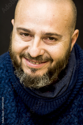 Handsome, bald man with beard on black background