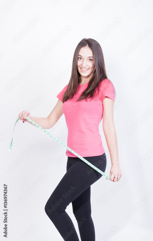 Athletic slim woman measuring her waist by measure tape after a diet over white background Athletic slim woman measuring her waist by measure tape after a diet over white background