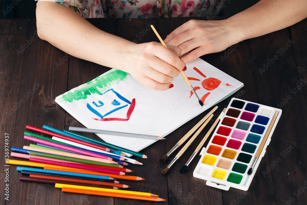 Woman drawing family house as concept of estate Woman drawing family house as concept of estate