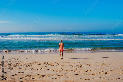 Beautiful surfer girl is enjoying vacation on the tropical beach. Young woman with surfboard in Sri Lanka.