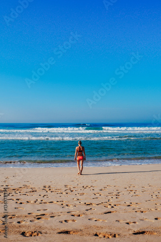 Beautiful surfer girl is enjoying vacation on the tropical beach. Young woman with surfboard in Sri Lanka.