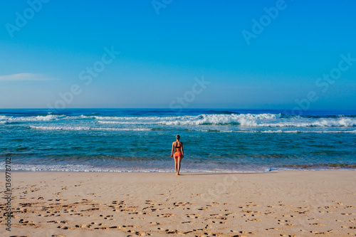Beautiful surfer girl is enjoying vacation on the tropical beach. Young woman with surfboard in Sri Lanka.