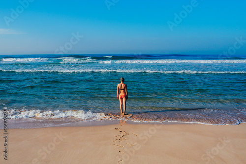 Beautiful surfer girl is enjoying vacation on the tropical beach. Young woman with surfboard in Sri Lanka.