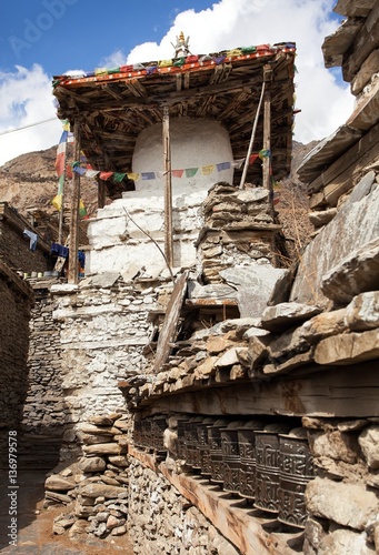 Stupa and prayer wheels wall in Manang villlage photo