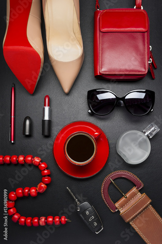 Woman accessories, clothing, jewelry, cosmetics in red color and cup of coffee on leather black background, lifestyle, modern female concept, fashion industry 