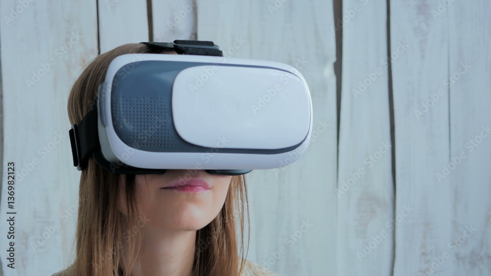 Young woman using Virtual Reality Glasses. Virtual reality mask. VR. White wooden background. Future and technology concept Young woman using Virtual Reality Glasses. Virtual reality mask. VR. White wooden background. Future and technology concept