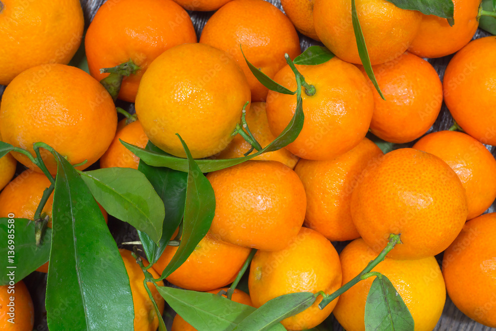 Tangerines with green leaves on the table closeup Tangerines with green leaves on the table closeup