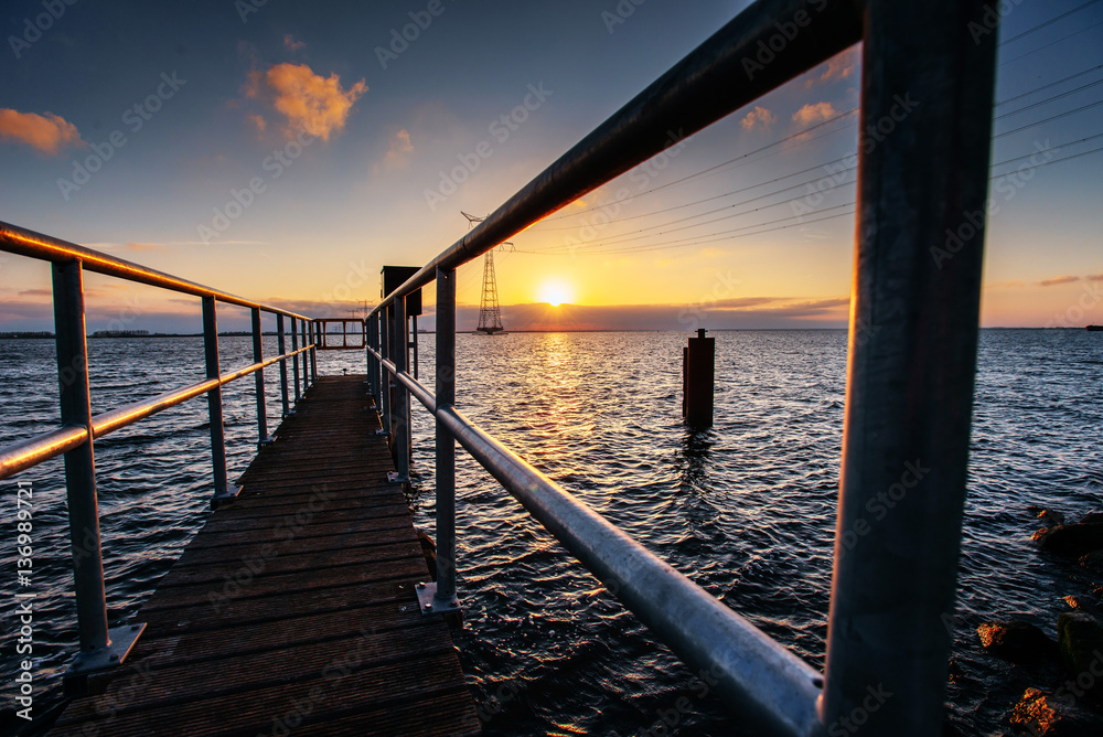 Fantastic sunset that illuminates the long pier on the lake