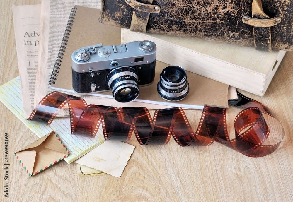 Φωτογραφία Old camera, film, lens and fragment of vintage satchel on wooden background