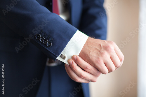 Closeup of a businessman with hands closing elegant blue suit jacket adjusts his cuffs