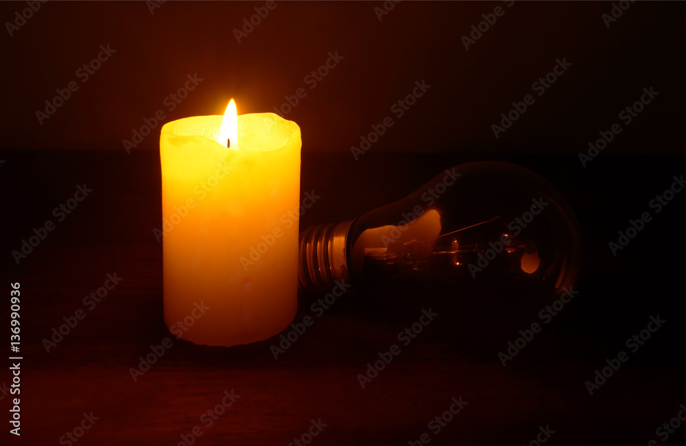 Burning candle and lamp on desktop in darkness (no electricity). Power outage.