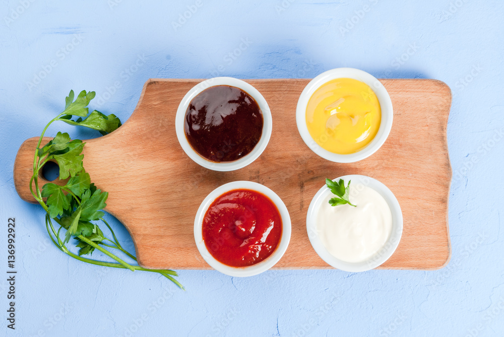 Classic set of sauces in white saucers: American yellow mustard, ketchup,  barbecue sauce, mayonnaise. On cutting board light blue stone concrete  table top view, copy space Stock Photo | Adobe Stock