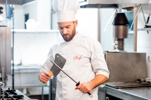 Portrait of chef cook in uniform with knifes at the restaurant kitchen