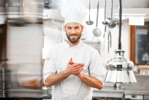 Portrait of handsome positive chef cook at the restaurant kitchen