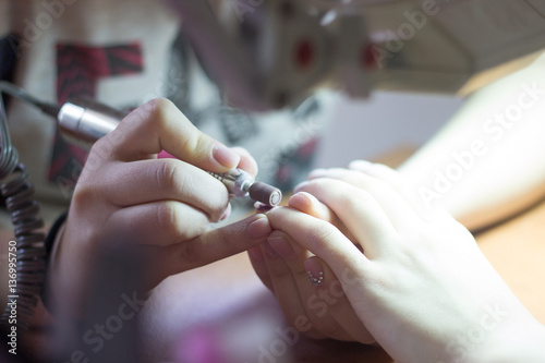 Manicurist makes manicure procedure with a machine on manicure t