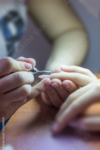 Finger nail care by manicurist to a girl client at beauty salon.
