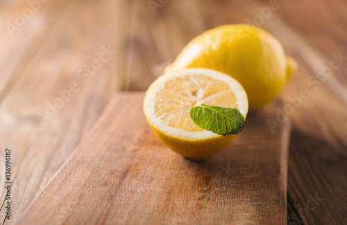 Half of lemon on a wooden board. Lemons  on a wooden background. Lemons. Fruits. Lemon halves. Mint. Healthy food concept. Copyspace