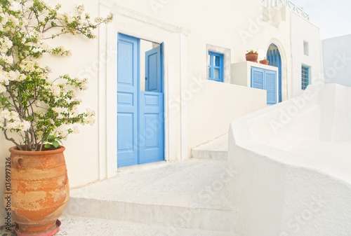 white Greek house with blue door and flower pot