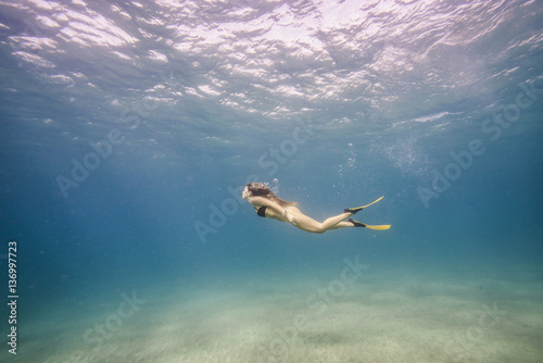 Side view of a woman swimming undersea