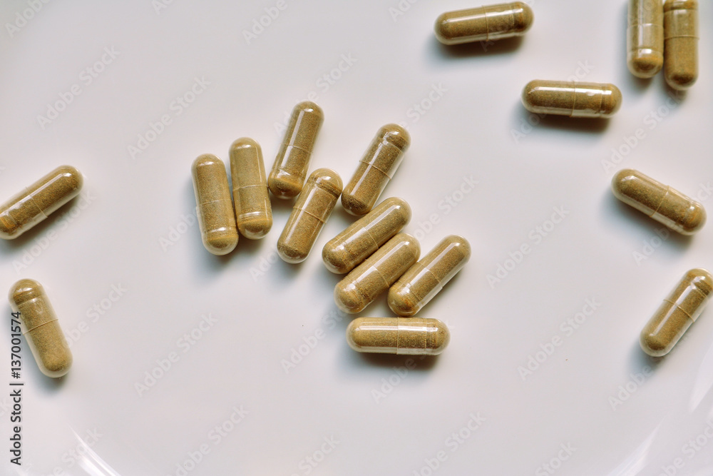 A bunch of green tea pills scattered on a white surface A bunch of green tea pills scattered on a white surface