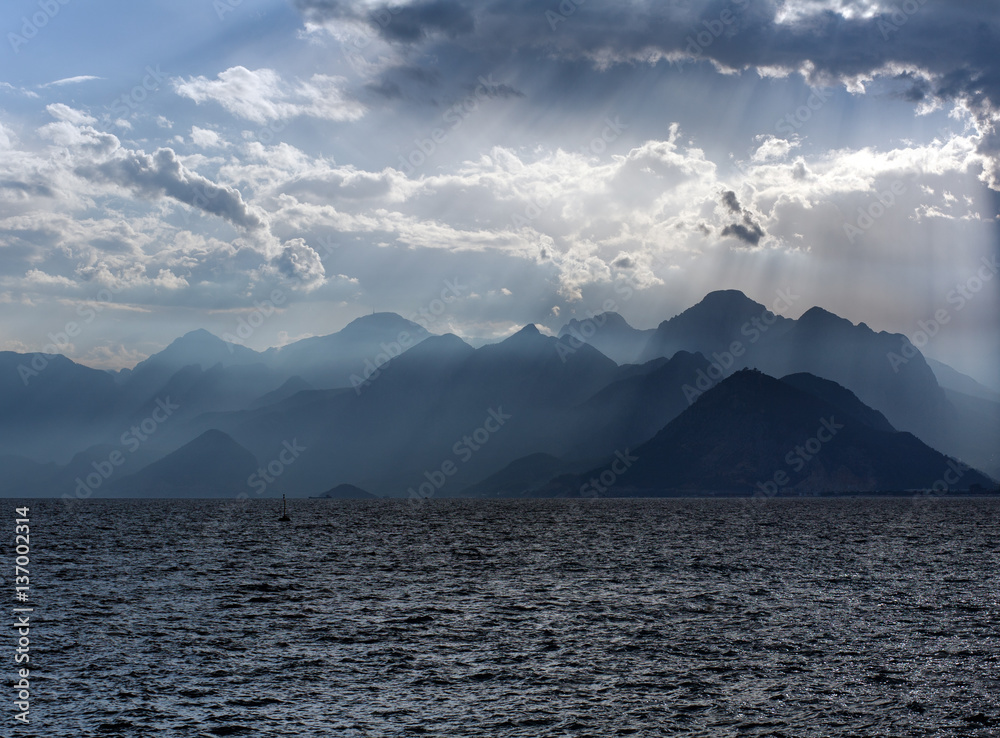 Scenery of sea and mountains on background of sky in sun rays