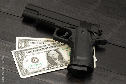 Black gun on banknotes. Concept of armed criminal offenses