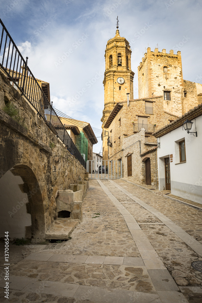 a street and the parish church in Iglesuela del Cid town, province of Teruel, Aragon, Spain