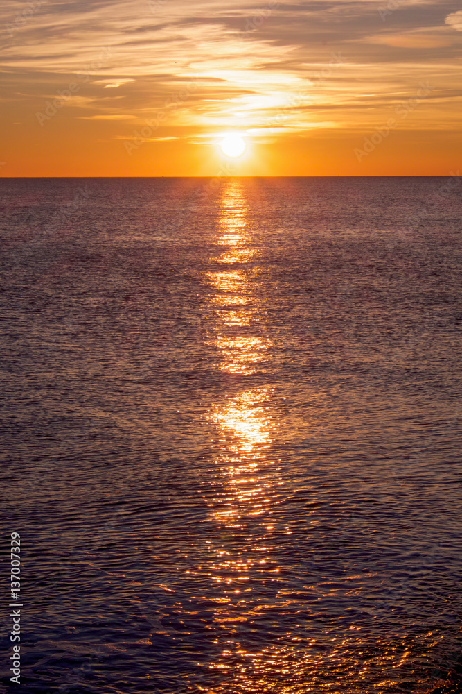 Obraz premium sunset casting long highlight over sea