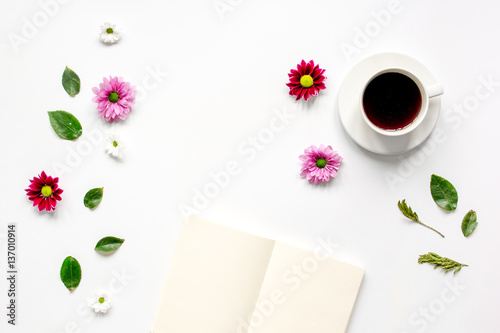 Coffee cup with flower petals and notebook top view mock-up