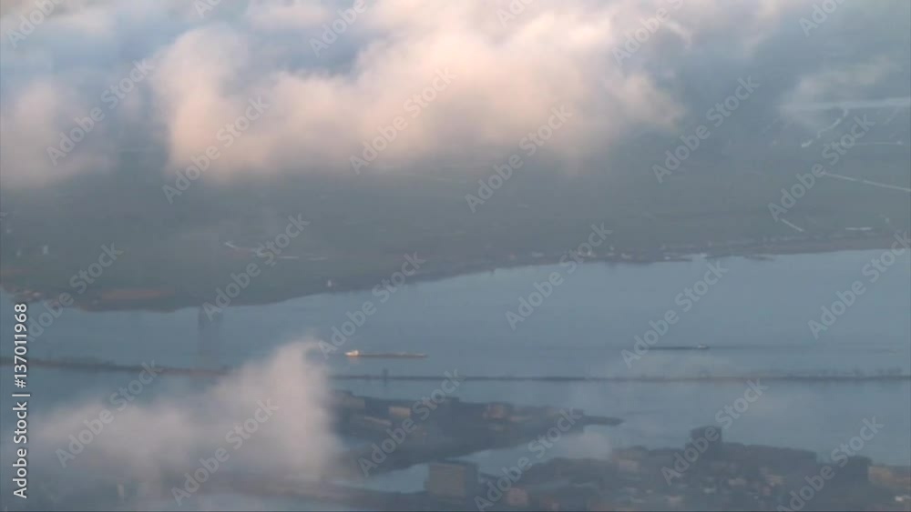 View of Amsterdam water canal from plane window throw the clouds, top view View of Amsterdam water canal from plane window throw the clouds, top view