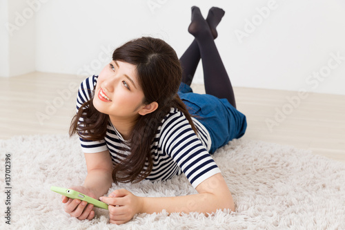 部屋でスマホを見る女性