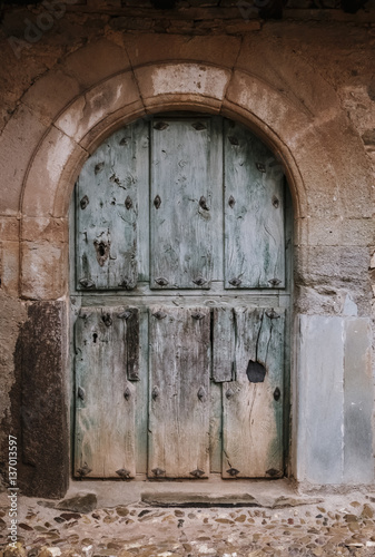 Old weathered wooden door in a stone wall in Castrillo de los Polvazares Leon, Spain