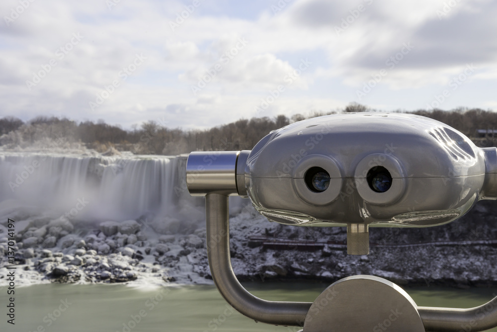 Tourist viewing binoculars at Niagara Falls with american waterf