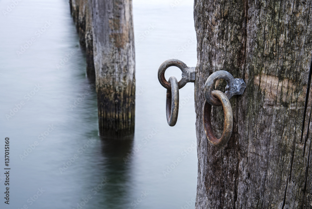 Φωτογραφία Weathered mooring poles of wood in the sea, detail with metal eyelets
