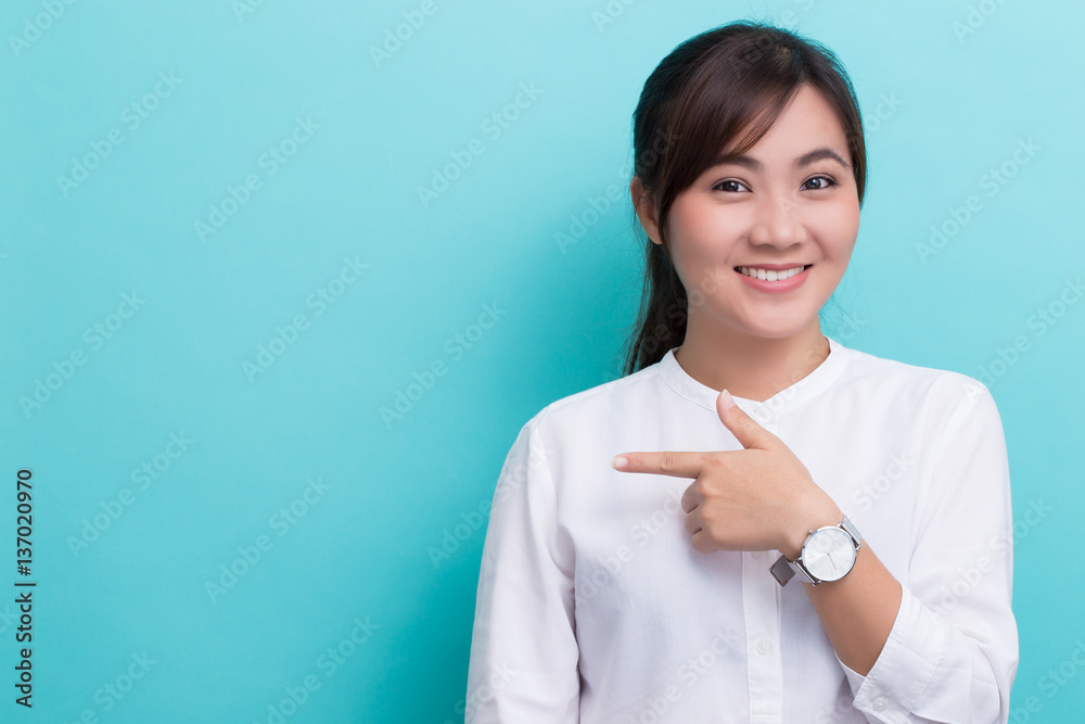 Asian woman pointing to the copy space isolated on blue backgrou Asian woman pointing to the copy space isolated on blue backgrou