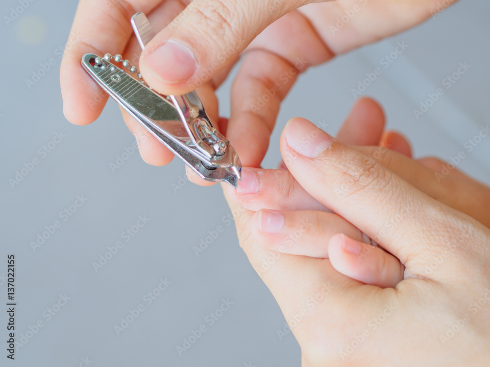 Family activity mother hand cut nails for kid by using nail clipper