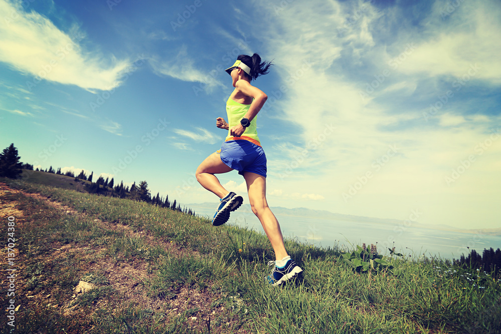 healthy lifestyle woman trail runner running on mountain peak