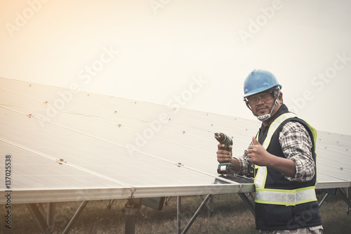 engineer or electrician working on maintenance equipment at solar power plant; engineer using driller working on Wrench tightening solar mounting structure of photovoltaic panel