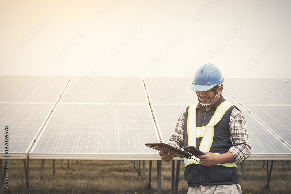 custom made wallpaper toronto digitalengineer or electrician working on maintenance equipment at industry solar power; engineer charging his phone with small solarcell at solar power plant