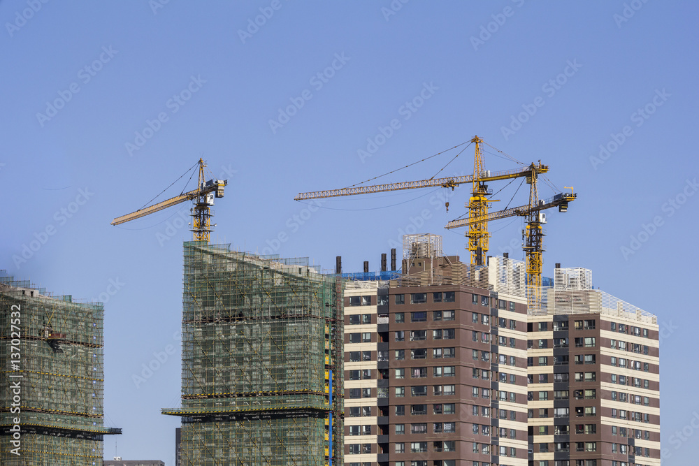 Three cranes working on top of a building in China Three cranes working on top of a building in China