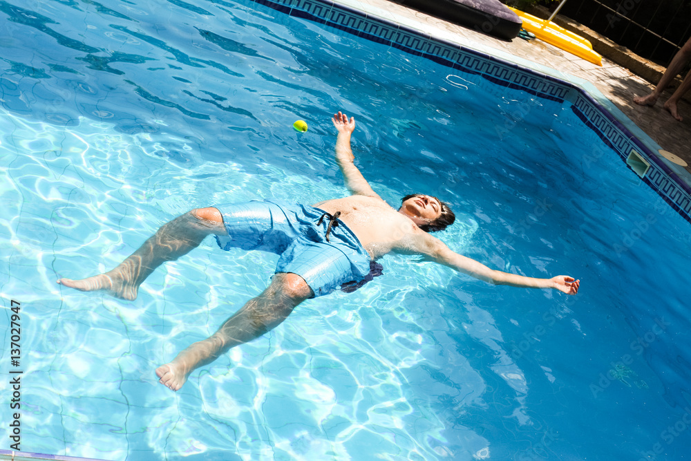 A man lying face up on a pool of clear water