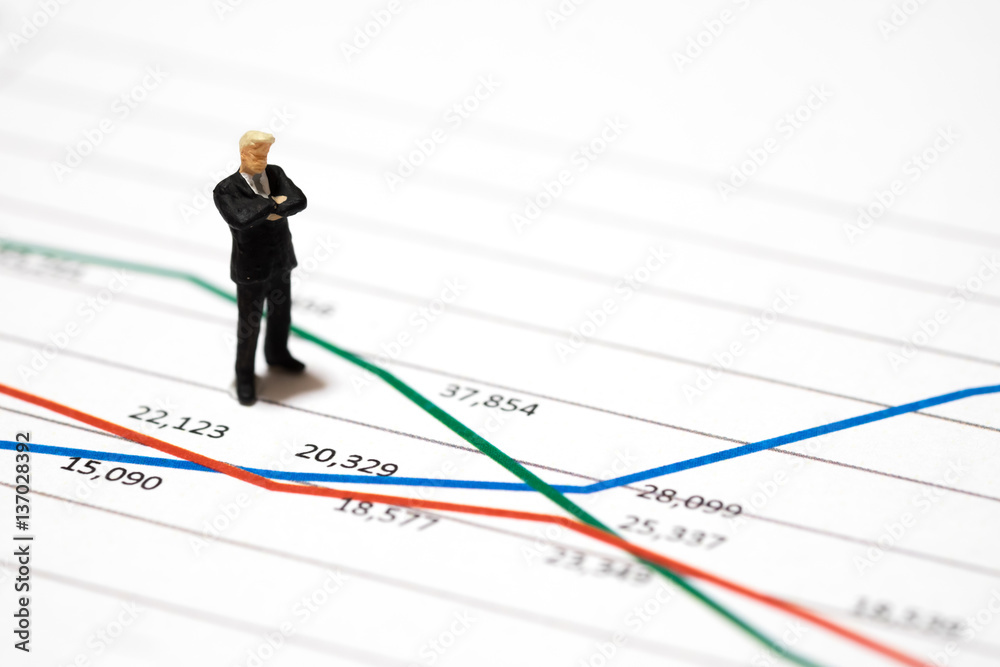 Miniature figures businessmen standing on a graph chart financial analysis review document with the team. Miniature figures businessmen standing on a graph chart financial analysis review document with the team.