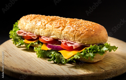 Sandwich with ham on a table, tomato and chees, homemade bread, black bacground