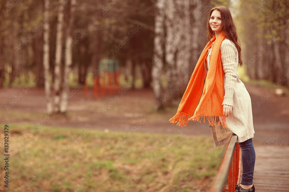 young girl in an orange scarf on a walk in the park