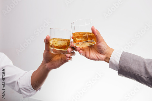 Two businessman in shirt and tie talking to each other while drinking whiskey after office hour