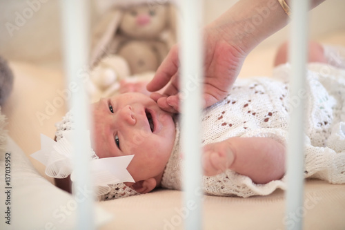 Cute newborn baby lies in the crib and looking mother