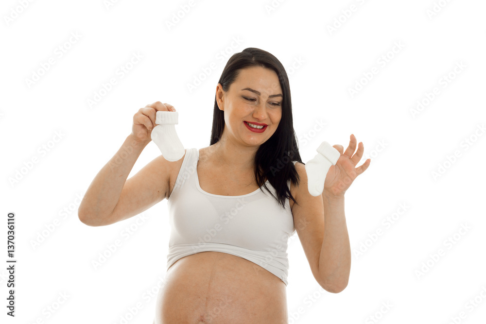 studio portrait of young pregnant brunette woman with little socks in her hands isolated on white background studio portrait of young pregnant brunette woman with little socks in her hands isolated on white background