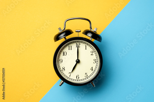 black vintage alarm clock on two tone color yellow and light blu