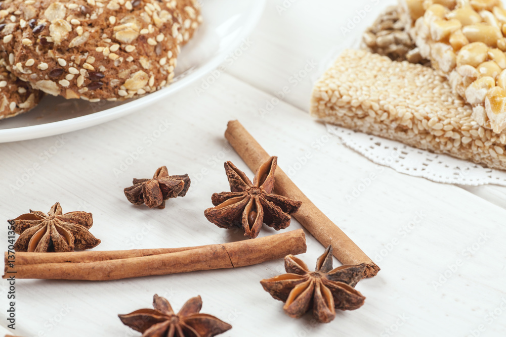 Cinnamon sticks with star anise on a white wooden table with sweet dessert on it Cinnamon sticks with star anise on a white wooden table with sweet dessert on it